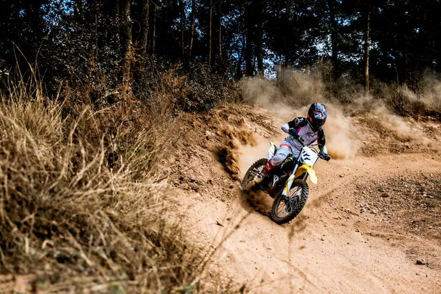 A rider leans into a dusty corner on a forest trail.